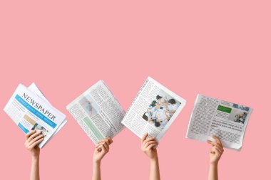 Pembe arka planda gazeteleri olan kadın eller.