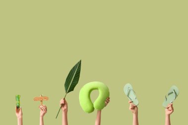 Plaj aksesuarları ve yeşil arka planda palmiye yaprağı olan kadın elleri. Turizm konsepti