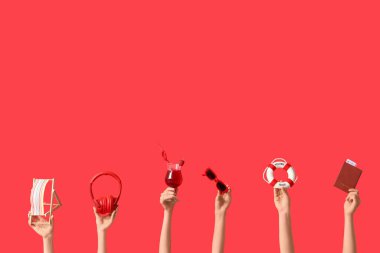 Kırmızı arka planda plaj aksesuarları olan kadın eller. Turizm konsepti