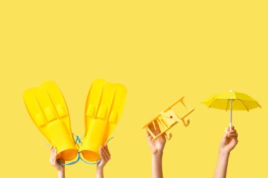 Paletli kadın eller, sarı arka planda oyuncak uçak ve şemsiye. Turizm konsepti