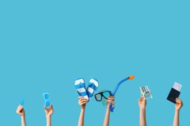 Mavi arka planda plaj aksesuarları olan kadın eller. Turizm konsepti