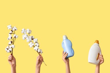 Pamuk çiçekli kadın elleri ve sarı arka planda çamaşır deterjanları.