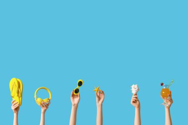 Mavi arka planda plaj aksesuarları olan kadın eller. Turizm konsepti