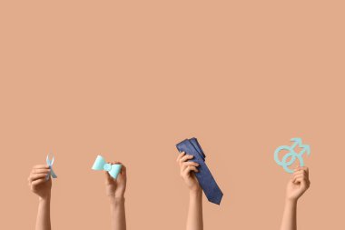 Mavi kurdeleli kadın eller, erkek sembolleri ve bej arka planda aksesuarlar. Prostat Kanseri Farkındalığı Ayı