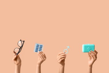 Erkeğin sembolü olan kadın elleri, bej arka planda haplar ve gözlükler. Prostat Kanseri Farkındalığı Ayı