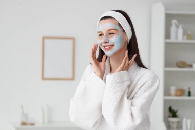 Kaplıca salonunda kilden maskeli güzel, genç ve mutlu bir kadın.