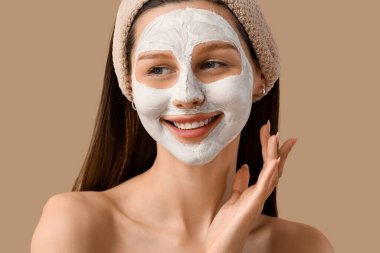 Bej arka planda kilden maskesi olan güzel, mutlu genç bir kadın.