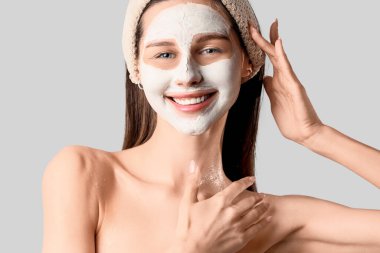 Gri arka planda kilden maskesi olan güzel, mutlu genç bir kadın.