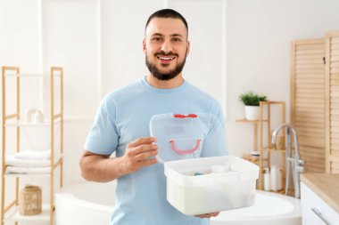 Banyoda ilk yardım çantası olan genç bir adam var.