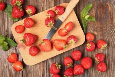 Tahta kesme tahtası olgun çilekler ve ahşap arka planda nane yaprakları