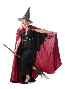 Beyaz arka planda süpürgesi olan cadı gibi giyinmiş mutlu olgun bir kadın. Cadılar Bayramı