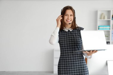Ofiste dizüstü bilgisayarı olan kulaklık takan kadın teknik destek ajanı.