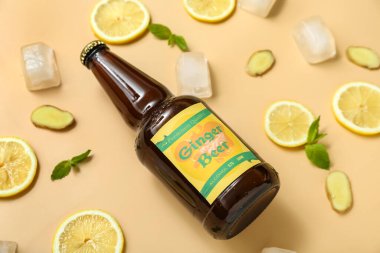 Bej arka planda taze zencefilli bira, nane, limon dilimleri ve buz küpleriyle kompozisyon, yakın plan.