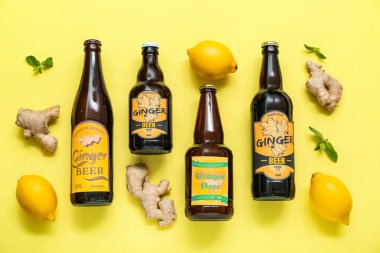 Farklı zencefilli bira, limon ve nane içeren kompozisyon sarı arka planda.