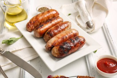 Beyaz ahşap arka planda ızgara sosis tabağı.