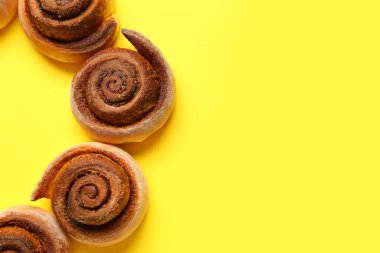 Sarı zemin üzerinde lezzetli tarçınlı rulolardan yapılmış çerçeve