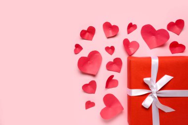 Hediye kutulu kompozisyon ve pembe arka planda kırmızı kağıt kalpler. Sevgililer Günü kutlaması