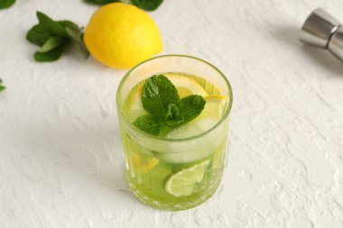 Bir bardak nefis limonata ve beyaz arka planda limon dilimleri.
