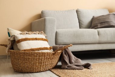 Rahat bir kanepe, sepette yastıklar ve oturma odasında çiçekler.