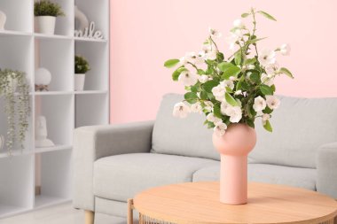 Rahat kanepesi, sehpası ve çiçek açan ağaç dalları olan şık bir oturma odası.