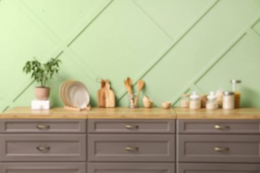 Tezgahları, yemek kavanozları ve çatal bıçakları yeşil duvarın yanında olan modern mutfağın bulanık görüntüsü.