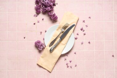 Pembe arka planda leylak çiçekleri olan güzel bir masa.