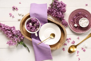 Beyaz ahşap arka planda leylak çiçekleri olan güzel bir masa.