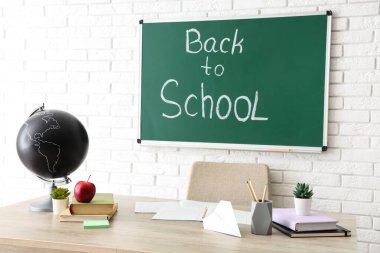 Sınıftaki öğretmen masasında elma, küre ve kırtasiye malzemesi var. Okul konseptine dönelim.