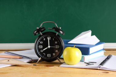 Elma, çalar saat, kitaplar ve karatahtanın yanındaki masada kağıt uçak. Okul konseptine dönelim.
