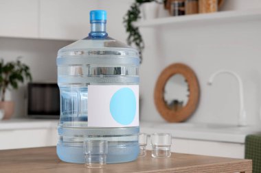 Mutfaktaki masada bir şişe temiz su ve bardaklar.