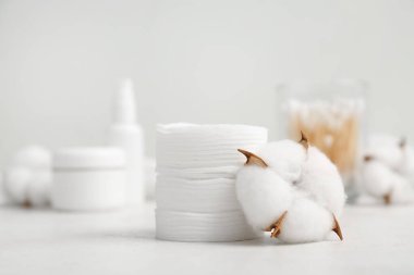 Kozmetik pedler, bezler, kozmetik ürünleri ve pamuk çiçekleri ışık masasında.