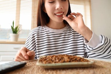 Genç Asyalı kadın mutfakta kızarmış böcek yiyor, yakın plan.