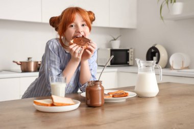 Yüzü lekeli, tatlı çikolata ezmeli tost yiyen tatlı bir kız.