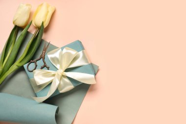 Laleli hediye kutusu, bej arka planda ambalaj kağıdı ve makas. Uluslararası Kadınlar Günü