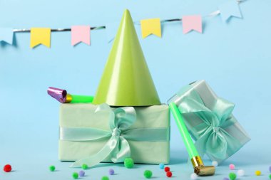 Parti şapkalı kompozisyon, hediye kutuları ve renk arkaplanlı ıslıklar