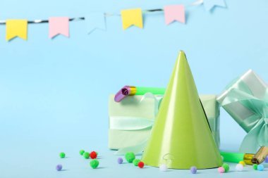 Parti şapkalı kompozisyon, hediye kutuları ve renk arkaplanlı ıslıklar