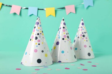 Parti şapkaları, konfeti ve arka planda kağıt çelenkler