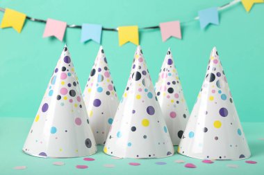 Parti şapkaları, konfeti ve arka planda kağıt çelenkler