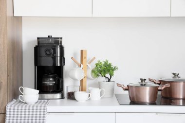 Modern kahve makinesi, fincanlar ve fasulyeler mutfakta tezgahta.