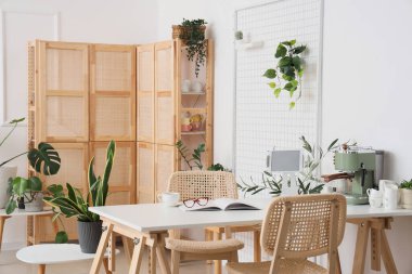 Masasında ev bitkileri, modern kahve makinesi ve tablet bilgisayar olan hafif mutfağın içi.