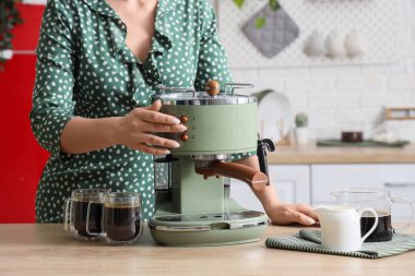 Mutfakta modern kahve makinesi kullanan genç bir kadın, yakın plan.
