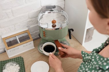 Mutfakta modern kahve makinesi kullanan genç bir kadın, yakın plan.