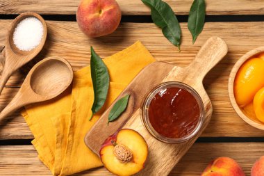 Lezzetli şeftali reçeli kavanozu ve ahşap arka planda taze meyveli kompozisyon