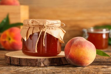 Bir kavanoz lezzetli şeftali reçeli ve ahşap masada taze meyve.