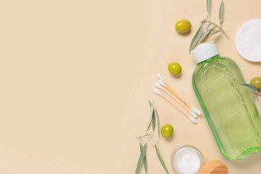 Doğal kozmetik ürünleri, pamuk pedleri, pamuklu çubuklar ve arka planda yeşil zeytinlerle kompozisyon