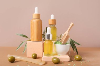 Renkli arkaplanda doğal yağ, deniz tuzu ve yeşil zeytin şişeleriyle kompozisyon