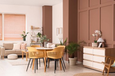 Gri kanepesi, yemek masası ve çiçekleri olan şık bir oturma odası.