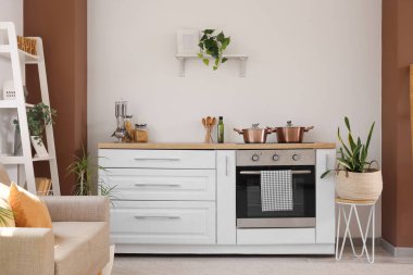 Gri kanepeli, raf üniteli ve tezgahlı şık bir açık uzay mutfağı.