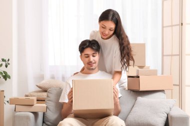 Paket kutularıyla evdeki kanepede oturan genç çift.