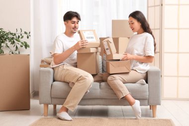 Paket kutularıyla evdeki kanepede oturan genç çift.